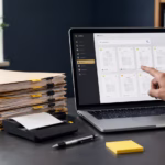 Paper records being scanned and organised into searchable digital records on a laptop.